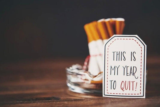 Smiling person holding a no smoking sign promoting Stoptober and oral health benefits of quitting smoking in October