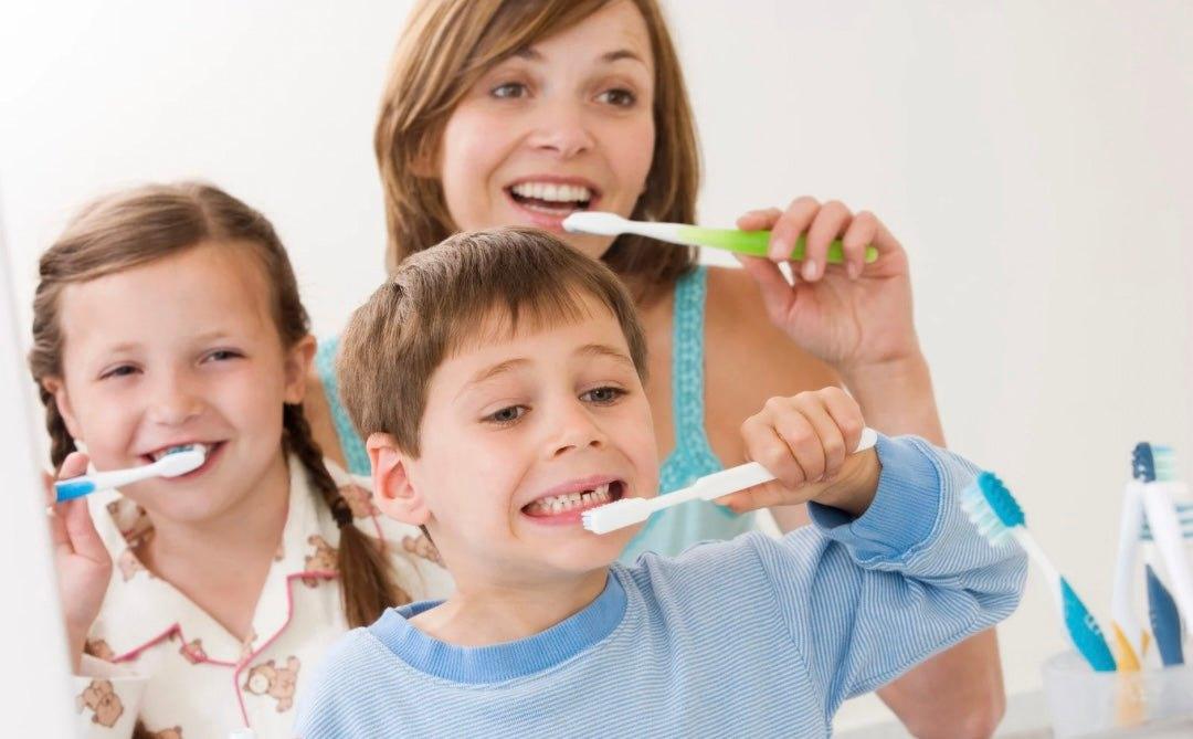 Child brushing teeth in winter morning with colorful toothbrush and smile