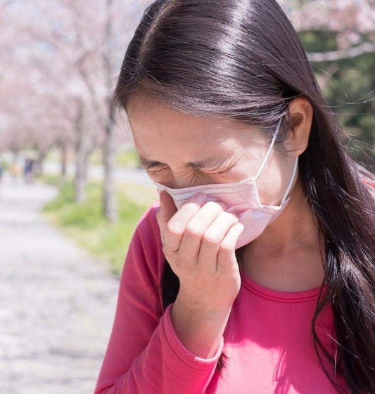 Person holding tissue near nose with allergy symptoms affecting oral health during hay fever season